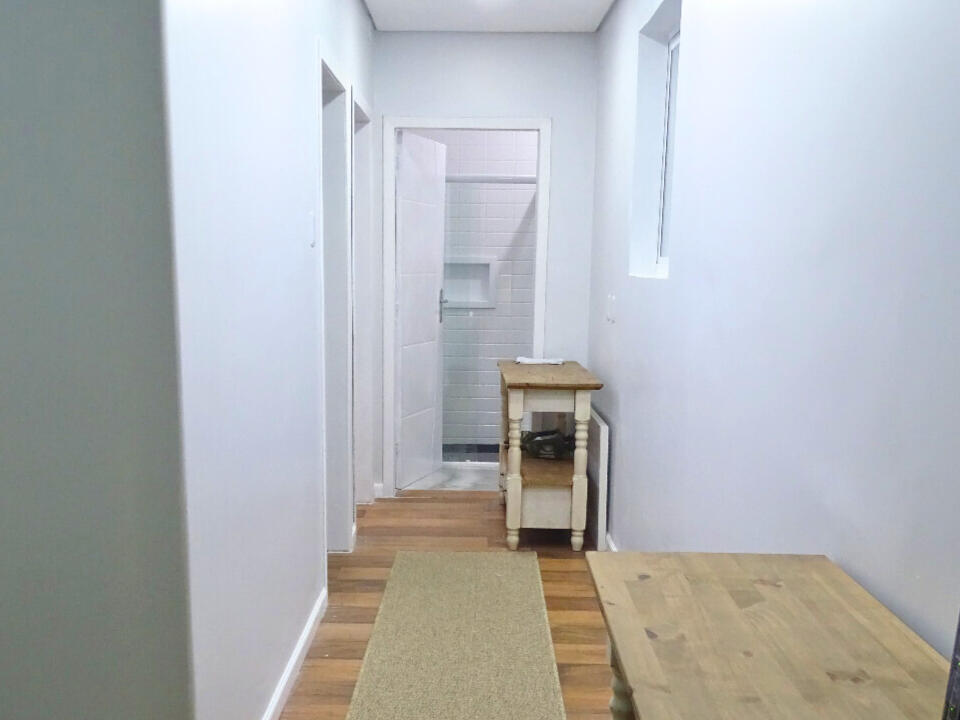 Foto do corredor do apartamento, com uma mesa para estudos e/ou trabalho e o roteador, e um aparador. Foto do corredor do apartamento, com uma mesa para estudos e/ou trabalho e o roteador, e um aparador.